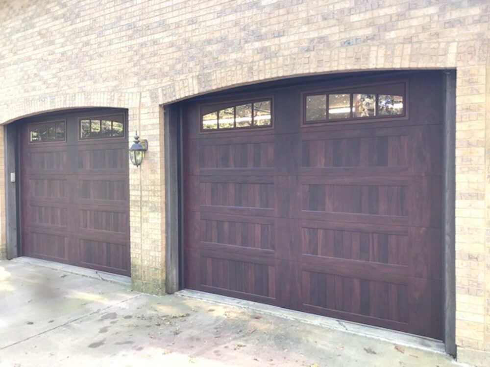 Dark woodgrain carriage-house double door on a brick home