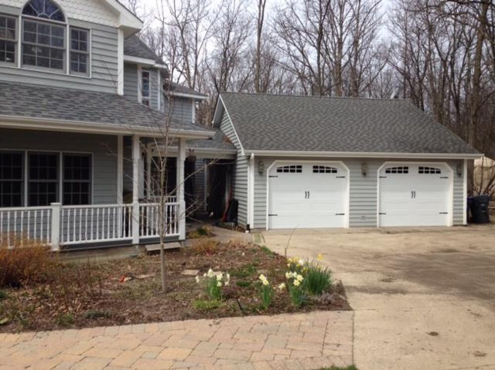Two-story home with white carriage-house garage doors