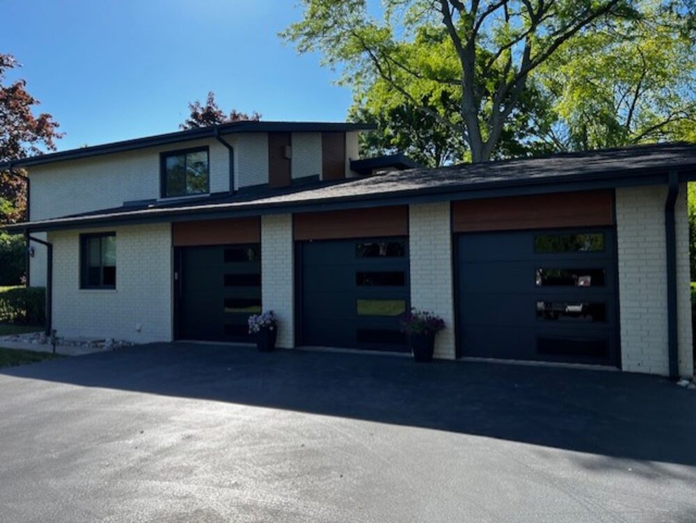 Suburban home with three dark modern-panel garage doors